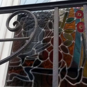 La photo montre une grande variété de types de verre, avec un relief qui suit souvent le dessin comme sur les feuilles vertes, les fleurs rouges peintes en dégradés et l'éclat de soleil jaune-orangé.