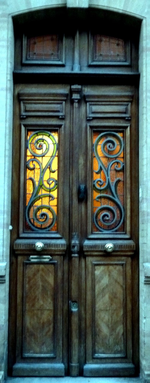 Les grilles de la porte précédente épousent étroitement le dessin du vitrail